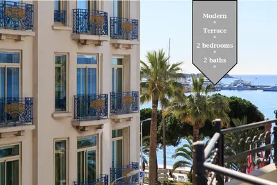 a building with blue balconies and palm trees and the ocean at MARTINEZ AREA: NEW 2BEDS/2BATHS in Cannes
