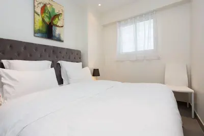 a white bed with white pillows and a window at MARTINEZ AREA: NEW 2BEDS/2BATHS in Cannes