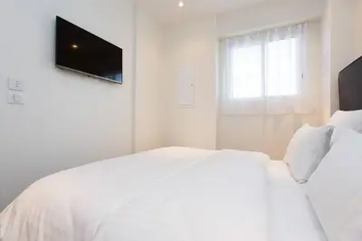 a white bedroom with a white bed and a television at MARTINEZ AREA: NEW 2BEDS/2BATHS in Cannes