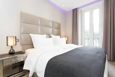 a white bedroom with a large bed and a window at 1 bedroom in front of the Palais! in Cannes