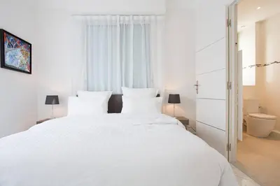 a white bedroom with a large white bed with white pillows at MARIOTT AREA: SUNNY 2 BEDS /2 BATHS in Cannes