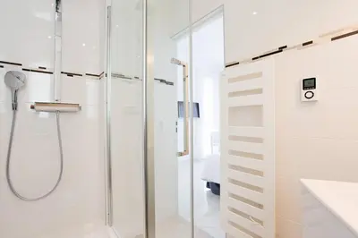 a white bathroom with a shower and a glass door at MARIOTT AREA: SUNNY 2 BEDS /2 BATHS in Cannes