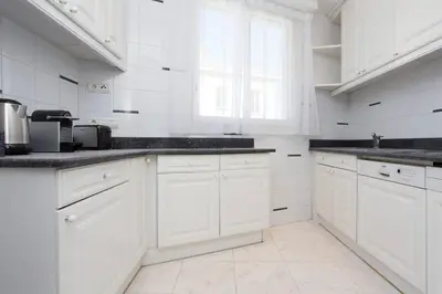 a white kitchen with white cabinets and black counter tops at MARIOTT AREA: SUNNY 2 BEDS /2 BATHS in Cannes