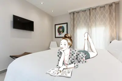 a woman sitting on a bed with a magazine at Marriott- Croisette: Superb 3 bedrooms/ 3 baths in Cannes