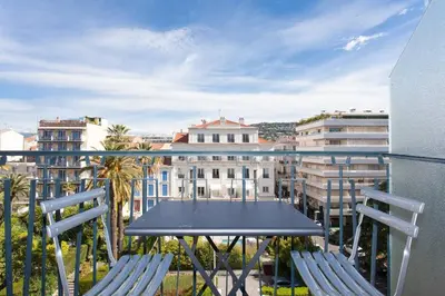 a table and chairs on a balcony with buildings at Marriott- Croisette: Superb 3 bedrooms/ 3 baths in Cannes