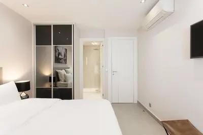 a white bedroom with a large white bed and a room at Marriott- Croisette: Superb 3 bedrooms/ 3 baths in Cannes