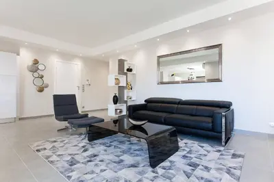 a living room with a black couch and a mirror at Marriott- Croisette: Superb 3 bedrooms/ 3 baths in Cannes