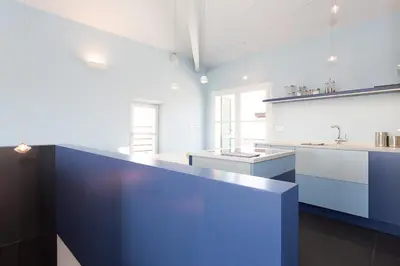 a large kitchen with white counters and blue cabinets at Top floor2 beds w/sea wiew in Cannes