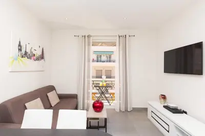 a white living room with a couch and a tv at Palais Miramar: 1 bed side sea view in Cannes