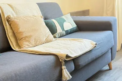 a blanket on a blue couch with pillows on it at 1-bedroom appartement in the center of Cannes in Cannes