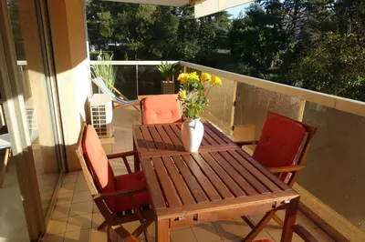 a wooden table with chairs and a vase of flowers on a balcony at Eden Beach in Cannes