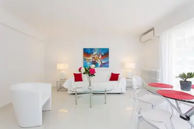 a white living room with a white couch and red pillows at MARRIOTT/ CROISETTE - LUXE 1 BED in Cannes