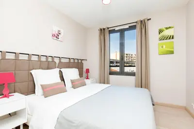 a white bedroom with a large bed and a window at 3 bedrooms: 200m from Croisette in Cannes
