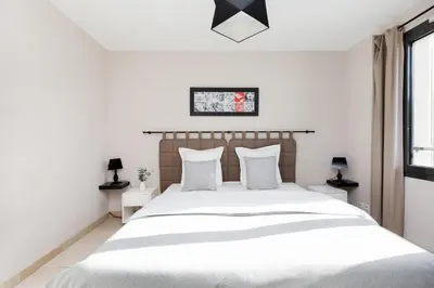 a white bedroom with a large bed with white pillows at 3 bedrooms: 200m from Croisette in Cannes