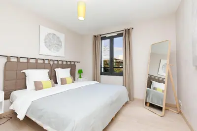 a white bedroom with a large bed and a mirror at 3 bedrooms: 200m from Croisette in Cannes