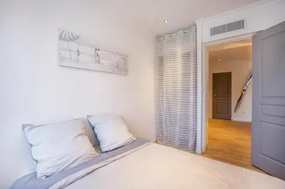 a white bedroom with a bed and a window at 3 pièces Luxe Croisette in Cannes