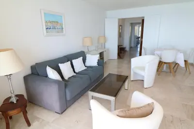 a living room with a blue couch and white chairs at Amazing sea view 2 bedroom beach front 303 in Cannes