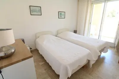 a white bedroom with two beds and a table at Amazing sea view 2 bedroom beach front 303 in Cannes