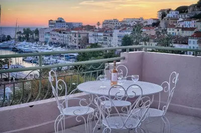 a table with wine bottles and chairs on a balcony at Superbe Duplex TERRASSE vue MER, FELIX FAURE- FORVILLE A1B059 in Cannes