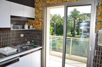 a kitchen with a sink and a balcony with palm trees at Karolina Properties - Ascot Appartement in Cannes