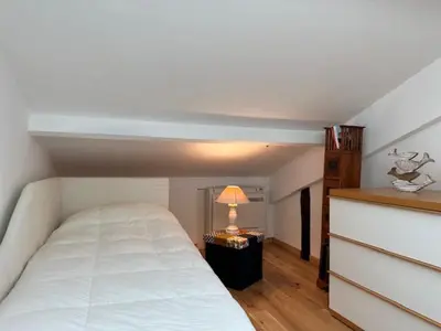 a bedroom with a white bed and a table with a lamp at Chez Nella in Cannes