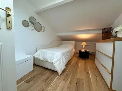 a bedroom with a white bed and a wooden floor at Chez Nella in Cannes
