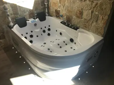 a white bath tub in a room with a stone wall at Love Room Jacuzzi Croisette in Cannes