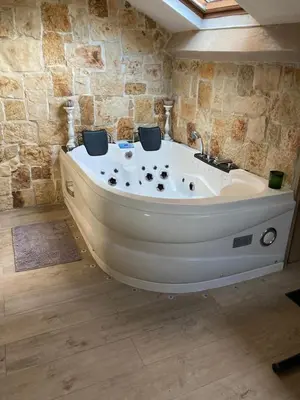 a bath tub in a room with a stone wall at Love Room Jacuzzi Croisette in Cannes