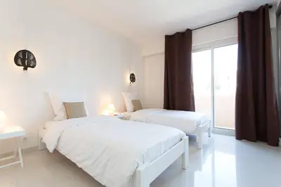 a white bedroom with two beds and a window at SEA VIEW 3 beds next to Palais in Cannes