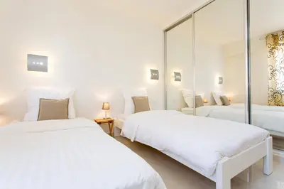 two beds in a white room with mirrors at SEA VIEW 3 beds next to Palais in Cannes