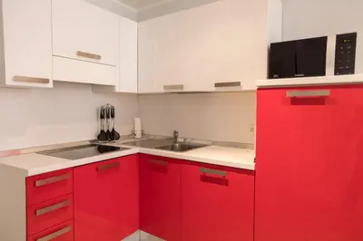 a red kitchen with a sink and a microwave at Résidence Bouttau by Connexion in Cannes
