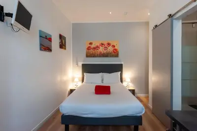 a bedroom with a bed with a red pillow on it at Hotel l'Hotera in Cannes