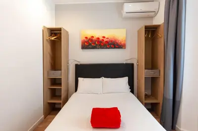 a bedroom with a bed with a red pillow on it at Hotel l'Hotera in Cannes