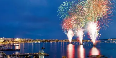 a fireworks display over a body of water with a city at Hotel America in Cannes