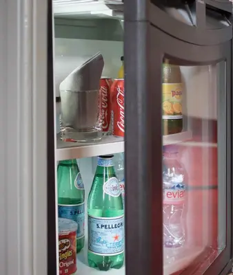 a refrigerator filled with bottles of soda and drinks at Hotel America in Cannes