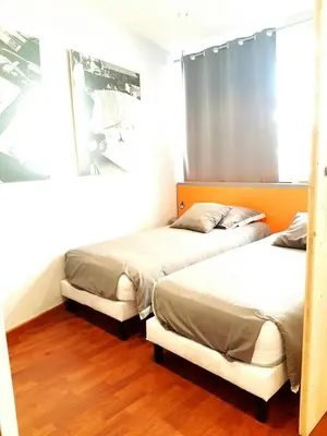 two beds in a room with wood floors at Latour Sea Cannes in Cannes