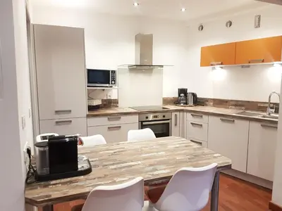 a kitchen with a wooden table and white chairs at Latour Sea Cannes in Cannes