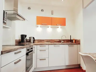a kitchen with white cabinets and an orange cabinet at Latour Sea Cannes in Cannes