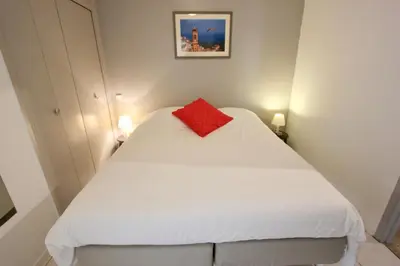 a small bedroom with a white bed with a red pillow at Fauvettes Sea Cannes in Cannes