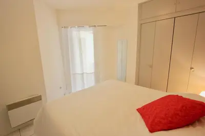 a bedroom with a white bed with a red pillow on it at Fauvettes Sea Cannes in Cannes