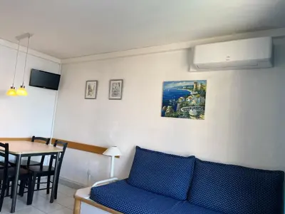a living room with a blue couch and a table at Cannes apartment with sea view, aircondition and parking in Cannes