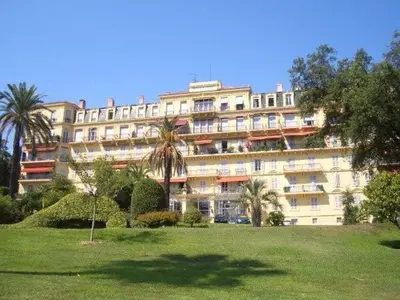 a large white building with palm trees in front of it at Appartement Claire Deluxe in Cannes