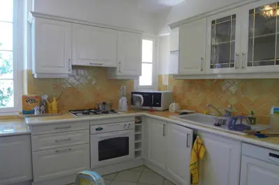 a kitchen with white cabinets and a sink and a microwave at Appartement Claire Deluxe in Cannes