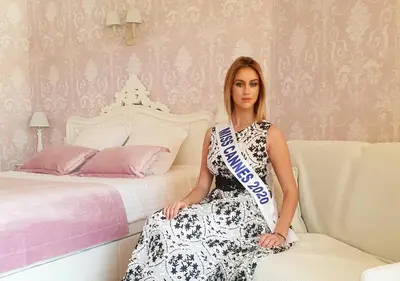 a woman in a dress sitting next to a bed at Palais Miramar Imperial Croisette in Cannes