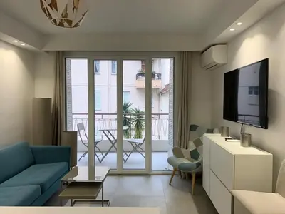 a living room with a blue couch and a television at Two bedroom Fragonard Cannes in Cannes