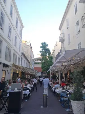 a group of people sitting at tables in a street at Appartements 7 Florian in Cannes