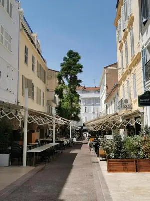 an empty street with tables and chairs and umbrellas at Appartements 7 Florian in Cannes