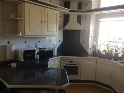 a kitchen with white cabinets and a black counter top at Inn CLOUDS Cannes in Cannes
