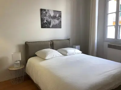 a bedroom with a bed with white sheets and a window at Vieux port de Cannes in Cannes