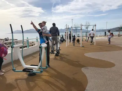 a woman holding a child on a exercise bike on a pier at Vieux port de Cannes in Cannes